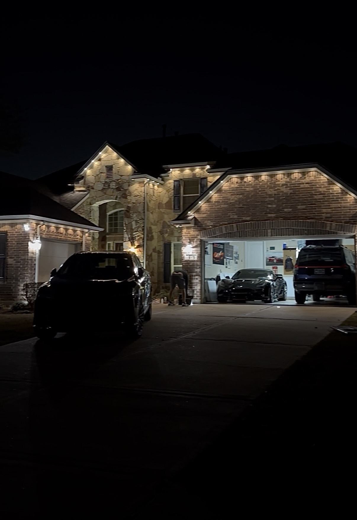 Stone and brick home with warm white roofline lighting at night