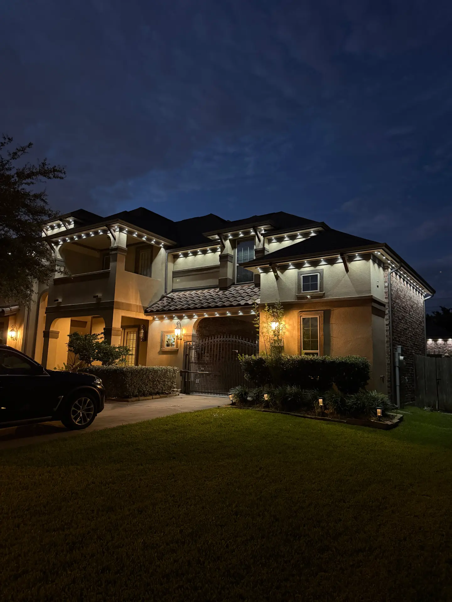 Stucco and brick home at night with warm white roofline LED lighting